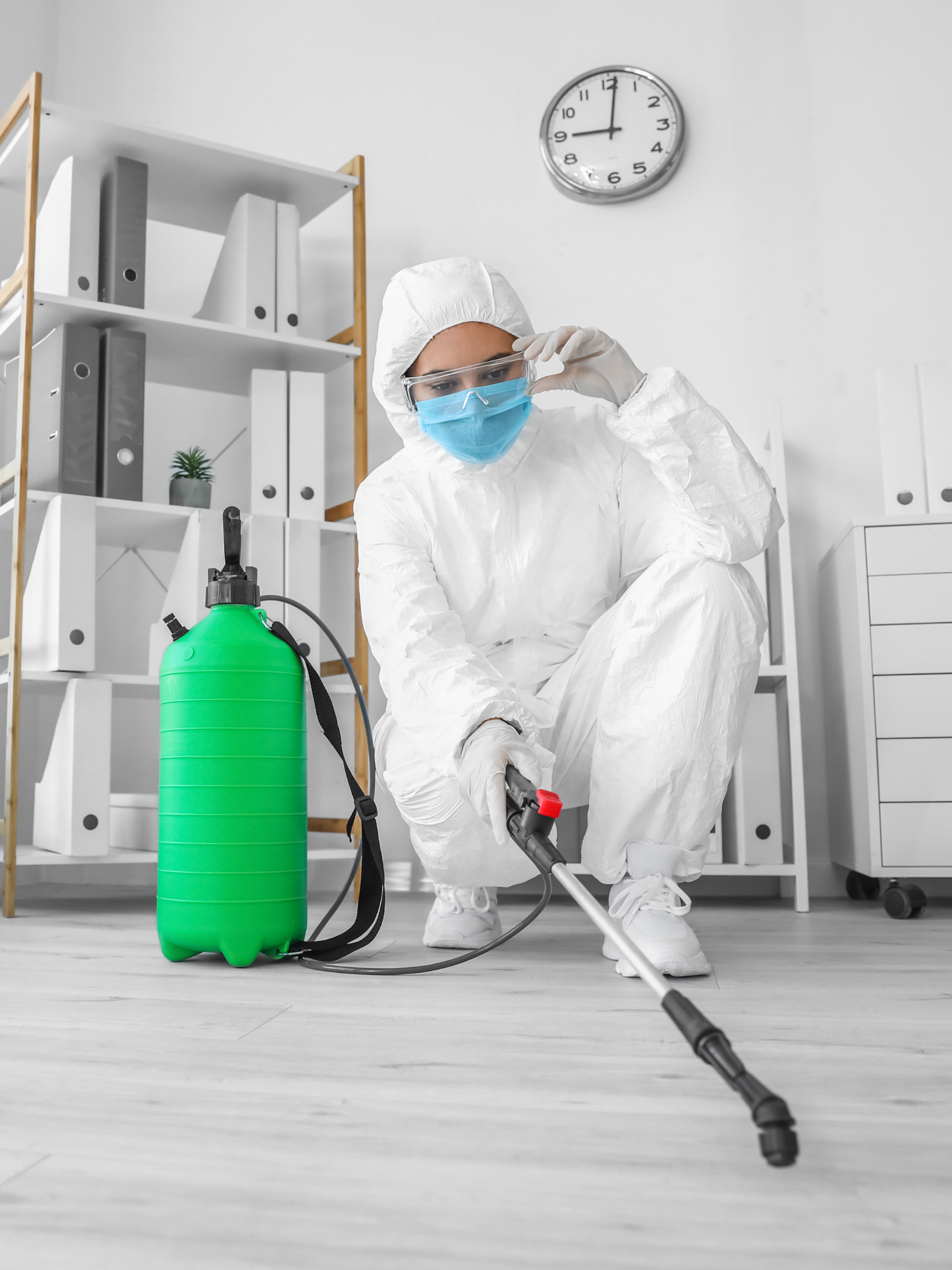 person wearing protective white clothing and a mask for disinfecting the area with a disinfecting cleaning machine